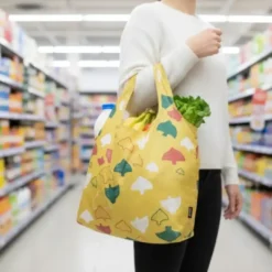 reusable foldable shopping bag with gold print, shown with matching compact pouch.